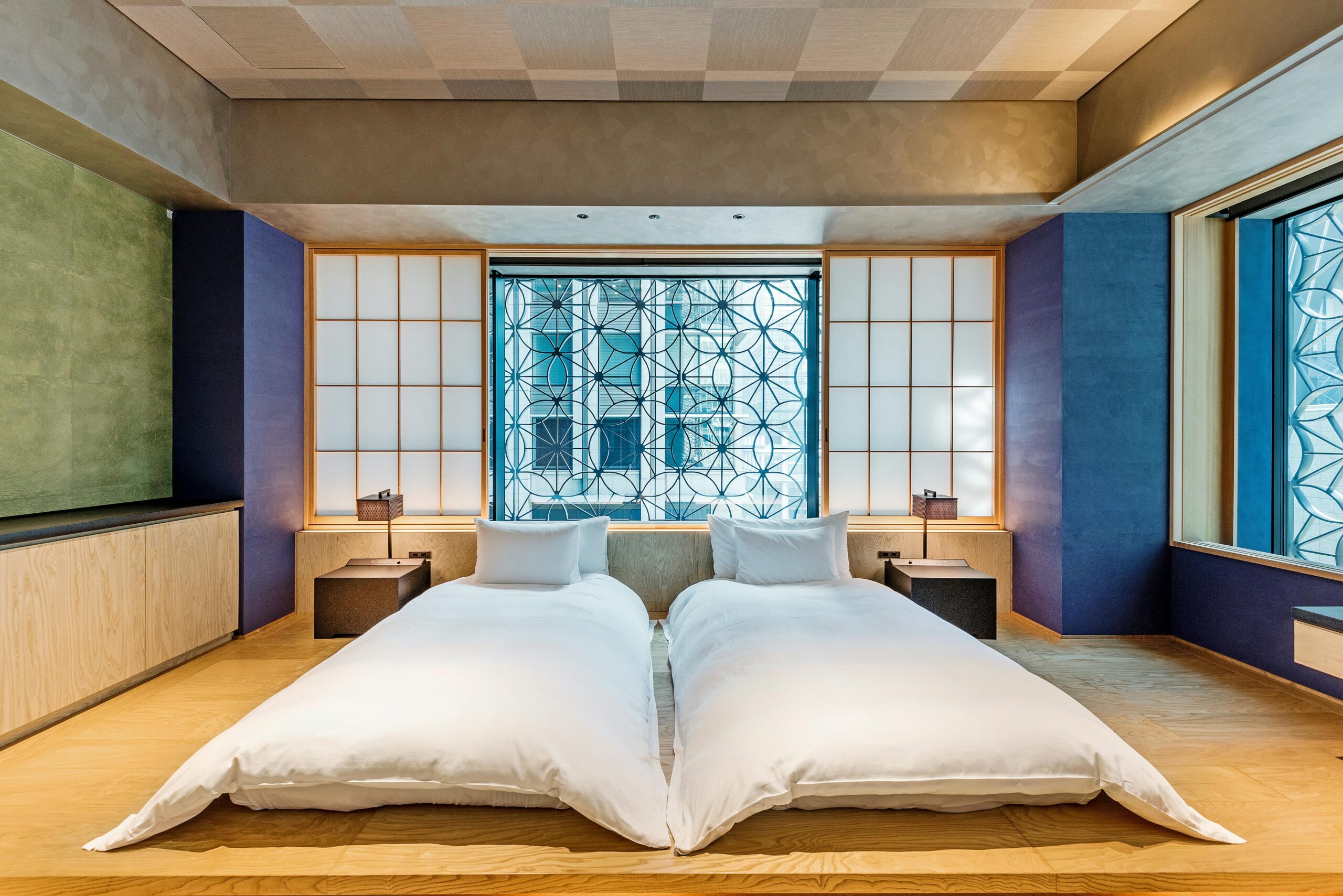 Modern hotel room with twin beds, minimalist design, and large windows with a city view